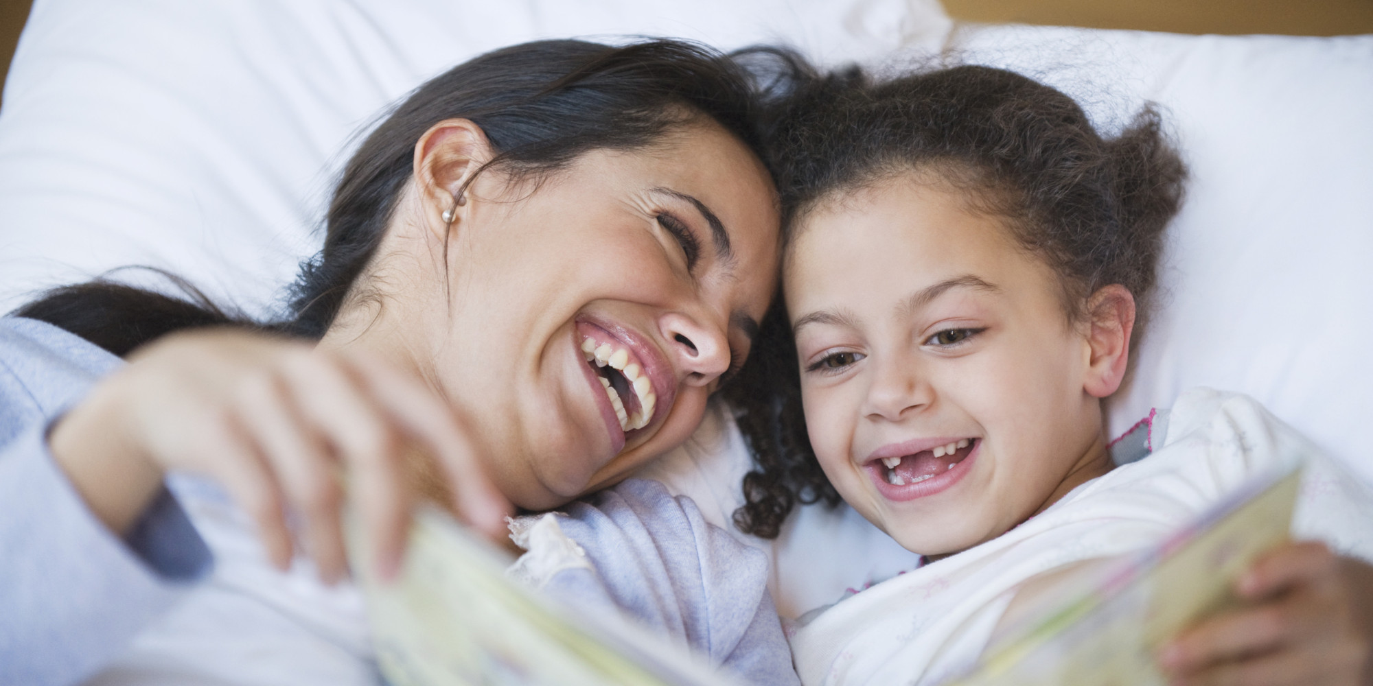 Hispanic mother reading book to daughter